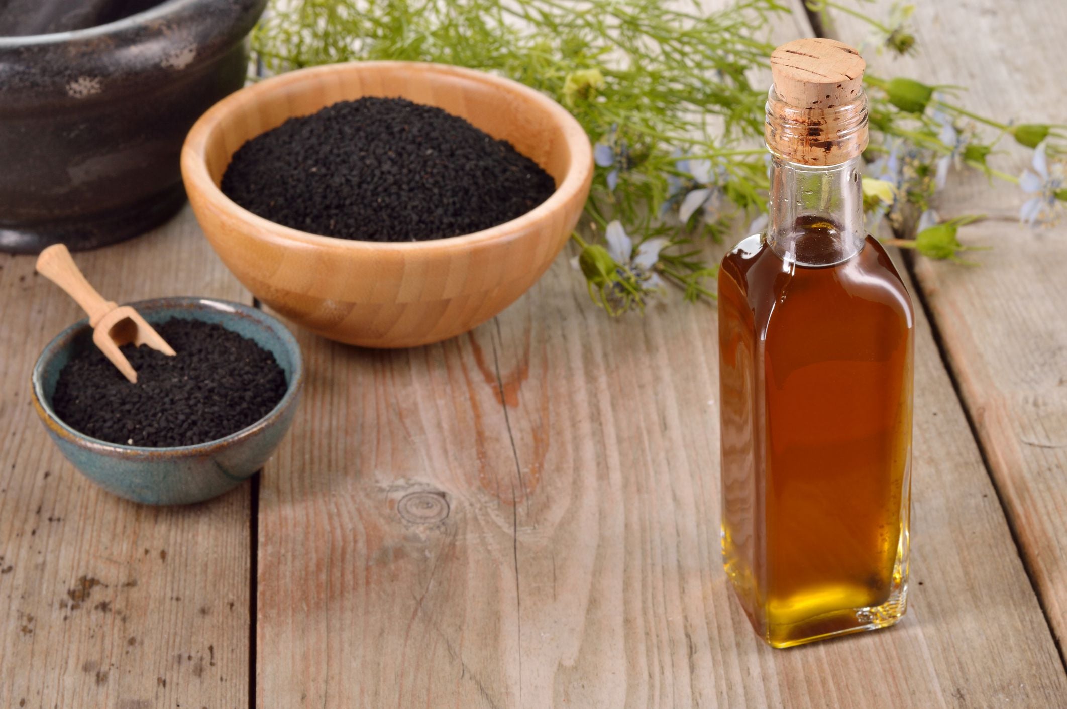 Black cumin seeds and black seed oil still life with bowls and bottle